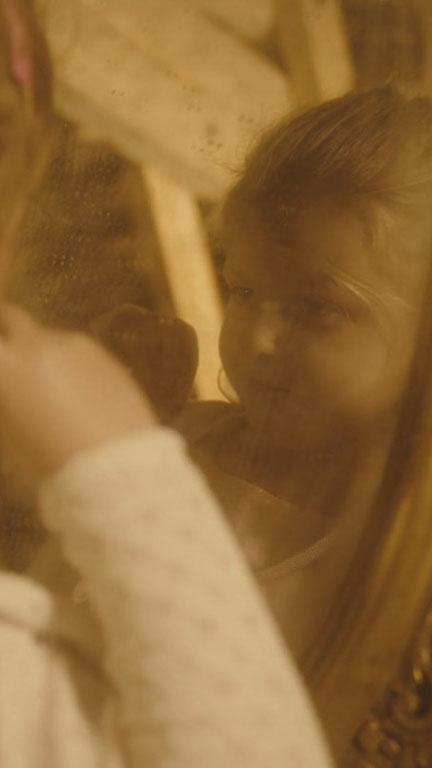 Photo d'une eptite fille se regarddant dans un miroir ancien